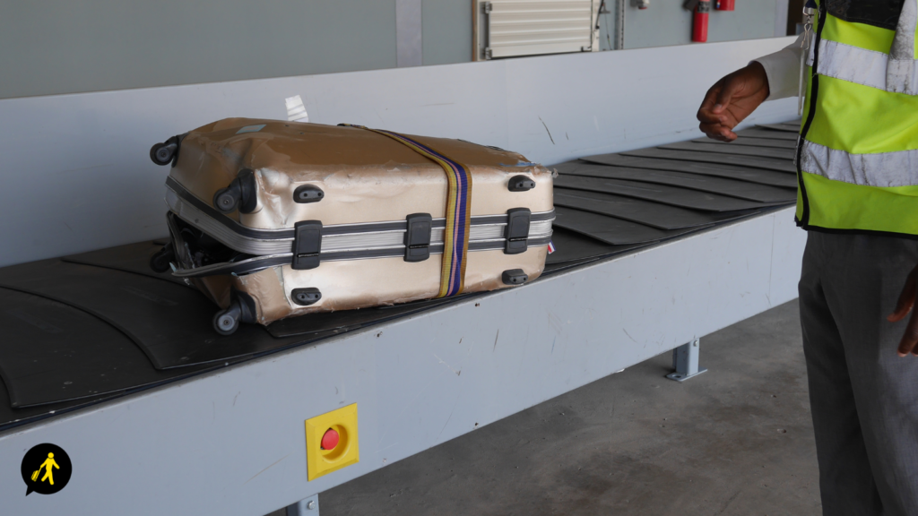 A significantly damaged suitcase on the baggage claim conveyor belt.