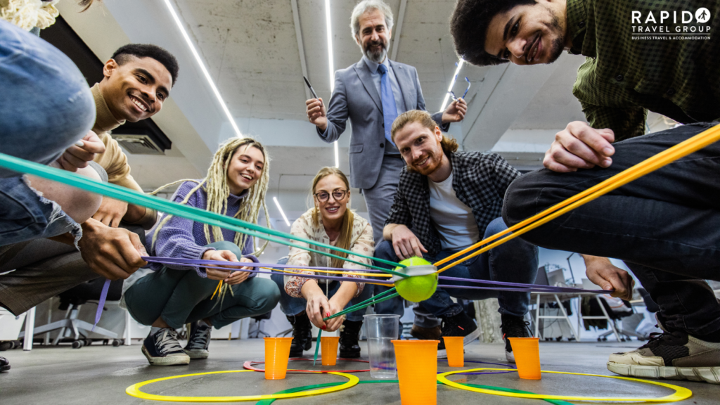 An example of a team-building activity featuring people each holding a rope attached to a tennis ball and guiding it to the correct cup on the floor.