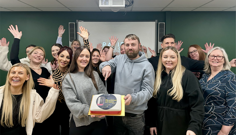 The Rapid team celebrating their ISO by cutting a celebration cake featuring the ISO 9001 badge