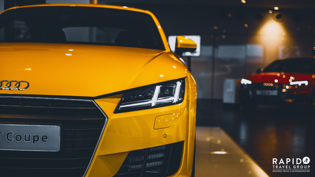 A yellow Audi Coupe in a dark showroom. A potential type of car you could hire.